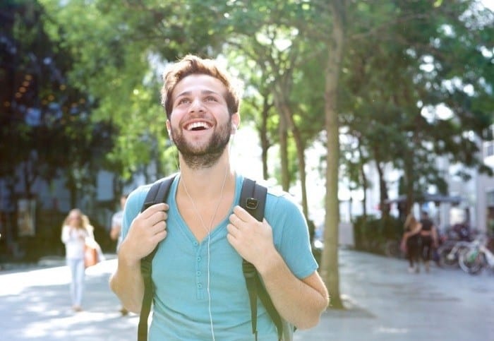 Um homem feliz carregando uma mochila.
